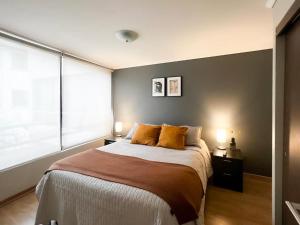 a bedroom with a large bed and a window at Depto CostaneraCenter in Santiago