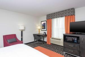 a hotel room with a bed and a tv and a desk at Hampton Inn Akron-South in Akron