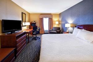 a hotel room with a bed and a flat screen tv at Hampton Inn Chicopee - Springfield in Chicopee
