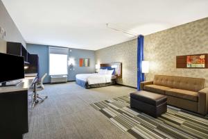 une chambre d'hôtel avec un lit et un canapé dans l'établissement Home2 Suites by Hilton Stow Akron, à Stow