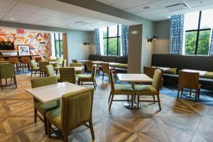 - une salle à manger avec des tables, des chaises et des fenêtres dans l'établissement Hampton Inn Cumberland, à Cumberland