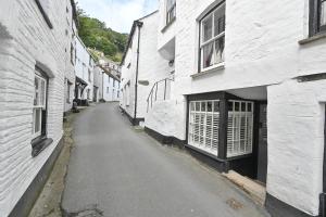 an empty street in an alley between two white buildings at Luxury Couple's Getaway with River Views and Parking in Polperro
