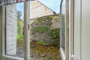 a window with a view of a brick wall at Luxury Couple's Getaway with River Views and Parking in Polperro