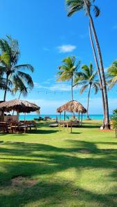 einen Park mit Tischen, Palmen und dem Meer in der Unterkunft Casa Grande Hotel Restaurant in Las Terrenas