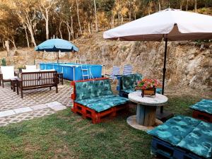 een patio met stoelen en een tafel met een parasol bij Chalet en entorno Natural de la Costa Brava in Bell-Lloch