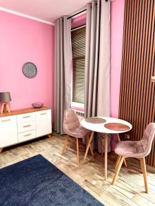Pokój ze stołem, krzesłami i różowymi ścianami w obiekcie Apartament Krasnostawski w mieście Krasnystaw