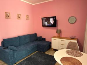a living room with a blue couch and a clock on the wall at Apartament Krasnostawski in Krasnystaw
