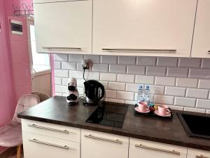 a kitchen with a black counter top and pink walls at Apartament Krasnostawski in Krasnystaw