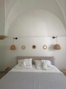 Una cama con sábanas blancas y almohadas. en LeVolte, en Brindisi