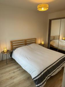1 cama en un dormitorio con 2 mesas y espejo en Nouveau! Maison avec Jacuzzi 1-8 pers à 10 mn de st Malo en Saint-Méloir-des-Ondes