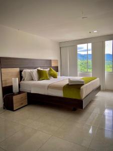 HOTEL RIVERA CENTRAL في بوكارامانغا: غرفة نوم بسرير كبير مع نافذة كبيرة