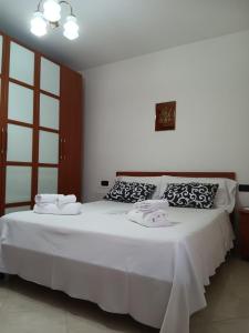 um quarto com uma cama branca e toalhas em Rita's House em Bivona