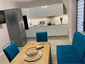 eine Küche mit einem Holztisch und blauen Stühlen in der Unterkunft Apartamenty Natalii in Nowy Targ