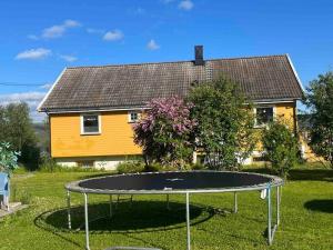 una pequeña casa amarilla con cama elástica en el patio en Hus med utsikt over Alta elva en Alta