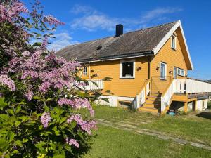 żółty dom z fioletowymi kwiatami przed nim w obiekcie Hus med utsikt over Alta elva w Alcie