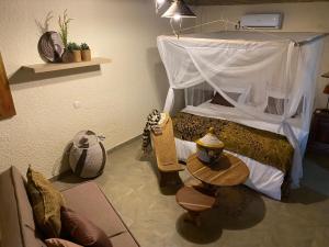 a bedroom with a bed with a canopy and a table at Toubacouta Lodges in Toubakouta