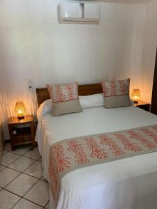 - une chambre avec un grand lit et deux lampes dans l'établissement Fare Manatea 19, à Papeete