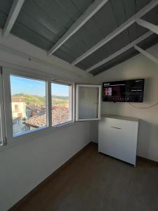 Habitación blanca con ventana grande y TV. en La Casetta di Treville en Ozzano Monferrato