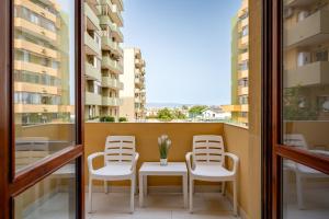 balcone con 2 sedie, tavolo e alcune finestre di Kalbia Apartment Renovated, functional, intimate and more a Cagliari