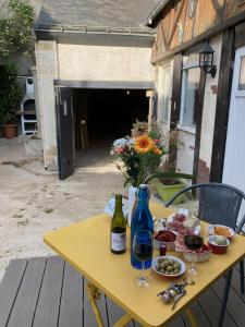 uma mesa amarela com comida e uma garrafa de vinho em Gîte cosy entre Tours et Amboise em Vernou-sur-Brenne