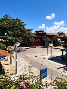 a park with tables and flowers in front of a building at Localização Incrível - Praia e Vila in Praia do Forte