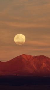 uma pintura da lua sobre uma montanha em Hotel Tulor em San Pedro de Atacama