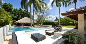 a swimming pool with white furniture and palm trees at Sunny Vacation Villa No 85 in San Rafael del Yuma