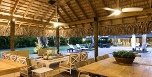 a patio with tables and chairs and a straw umbrella at Sunny Vacation Villa No 85 in San Rafael del Yuma