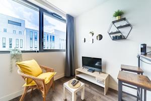 een woonkamer met een gele stoel en een tv bij Le Guérin cosy studio 2 pers Tête d'Or in Villeurbanne