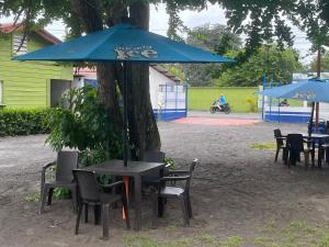 Hotel Chulamar, Piscina y Restaurante في Escuintla: طاولة وكراسي تحت مظلة بجانب شجرة