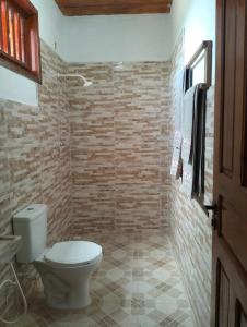 a bathroom with a toilet and a stone wall at Pousada Villa Marini in Itarema
