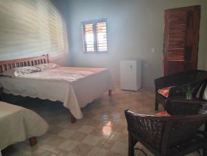 a bedroom with a bed and a chair and a window at Pousada Villa Marini in Itarema
