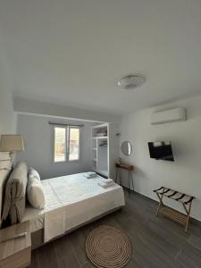 a white bedroom with a bed and a television at DK Square in Andros
