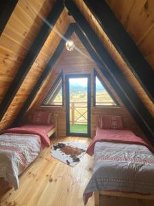 a attic room with two beds and a window at Runolist Chalet in Žabljak