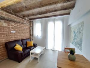een woonkamer met een bank en een bakstenen muur bij Antic Apartament in Manresa