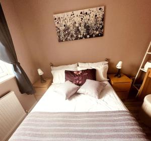 a bedroom with a white bed with two pillows at NKN cosy maisonette close to train station, food, shopping in Kent