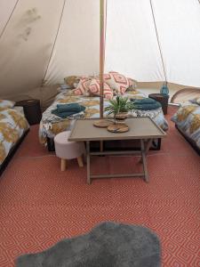 a room with two beds and a table in a tent at Stay Wild Retreats 'Glamping Pods and Tents' in Wrexham