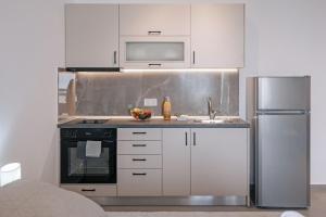 a kitchen with white cabinets and a stainless steel refrigerator at 777 Studios Corfu in Agios Ioannis
