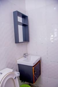 ein weißes Bad mit einem Waschbecken und einem WC in der Unterkunft Mwiza in Kigali