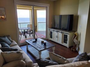 a living room with a couch and a television and a table at Grand Panama Beach Resort 1-1103 in Panama City Beach