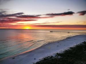 a sunset over a beach with a pier and the ocean at Grand Panama Beach Resort 1-1103 in Panama City Beach