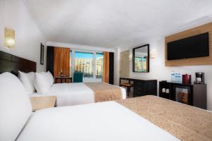カンクンにあるクリスタル カンクンのベッド2台、薄型テレビが備わるホテルルームです。