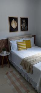 1 dormitorio con cama con almohada amarilla y mesa en Casa jardim para temporada em Piranhas-Alagoas, en Piranhas
