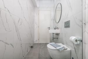 a white bathroom with a toilet and a mirror at 777 Studios Corfu in Agios Ioannis
