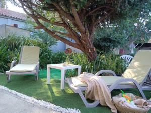 a patio with two chairs and a table and a tree at CASA DA VOVÓ CÉU - Casa de Campo Gandaresa - Country House, entre COIMBRA e AVEIRO, a 15 minutos carro Praia Mira - Quintal com piscina desmontável in Cantanhede