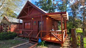 een kleine houten hut met een veranda in een tuin bij Cabañas Pulmahue in Colón