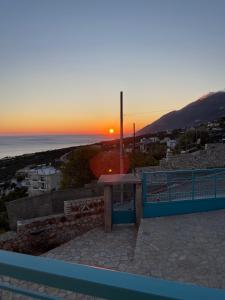 a sunset from the balcony of a house with a table at Endless blue Apartments in Dhërmi