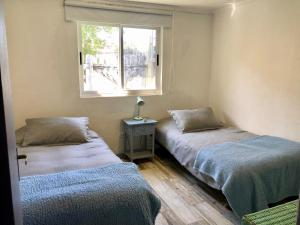 Dos camas en una habitación con ventana. en Casa Pichilemu, en Pichilemu 13 fotos más