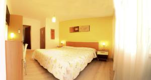 una camera con un letto e una parete gialla di Hotel Alpino a Malcesine