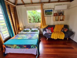 2 Betten in einem Zimmer mit Sofa und Fenster in der Unterkunft La kaz nature bien-être in Petit-Bourg